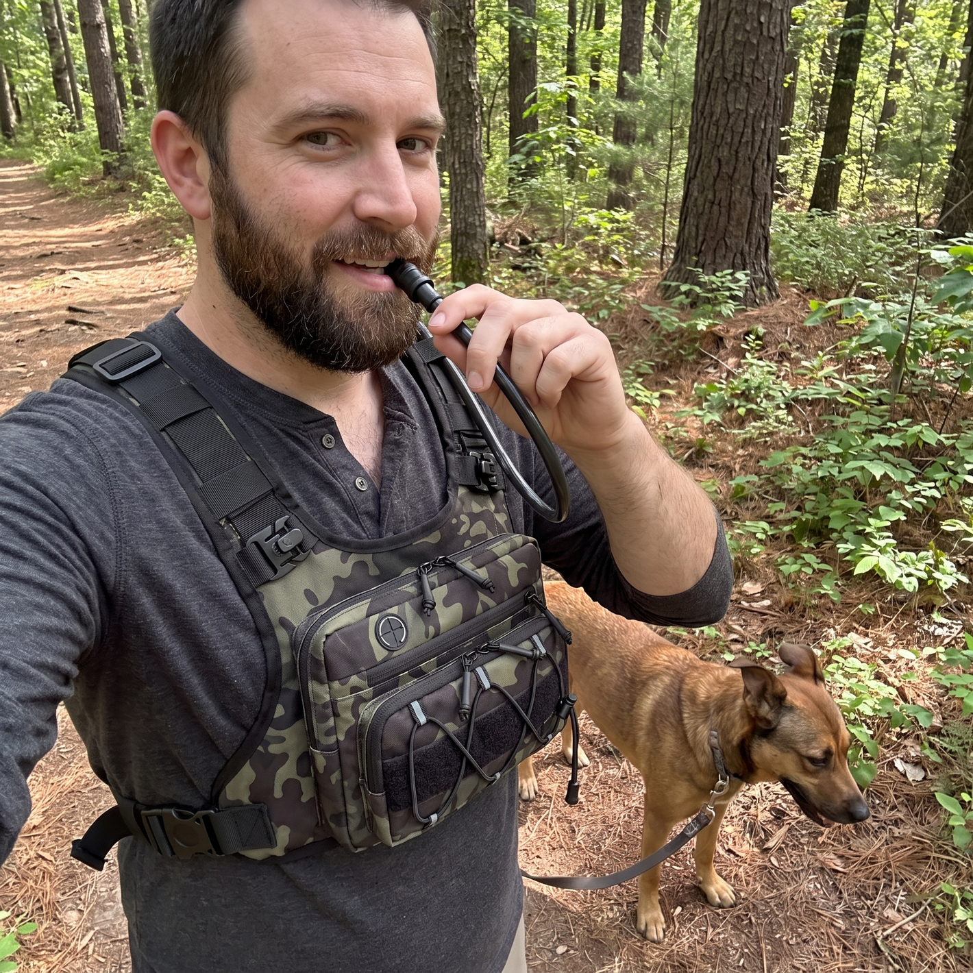 Customer hiking with dog wearing HydraKor camo hydration vest